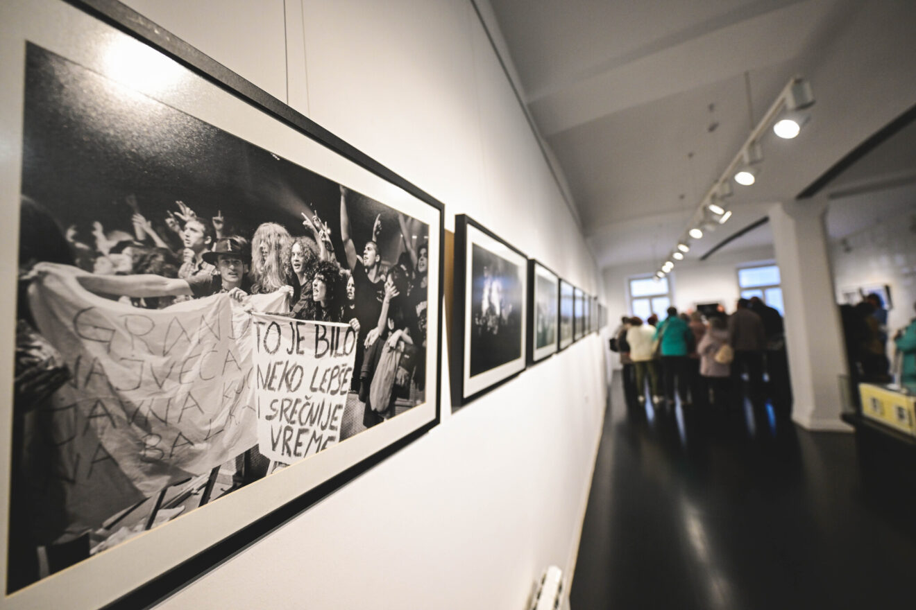 Fotografije v okvirju, v ozadju množica.