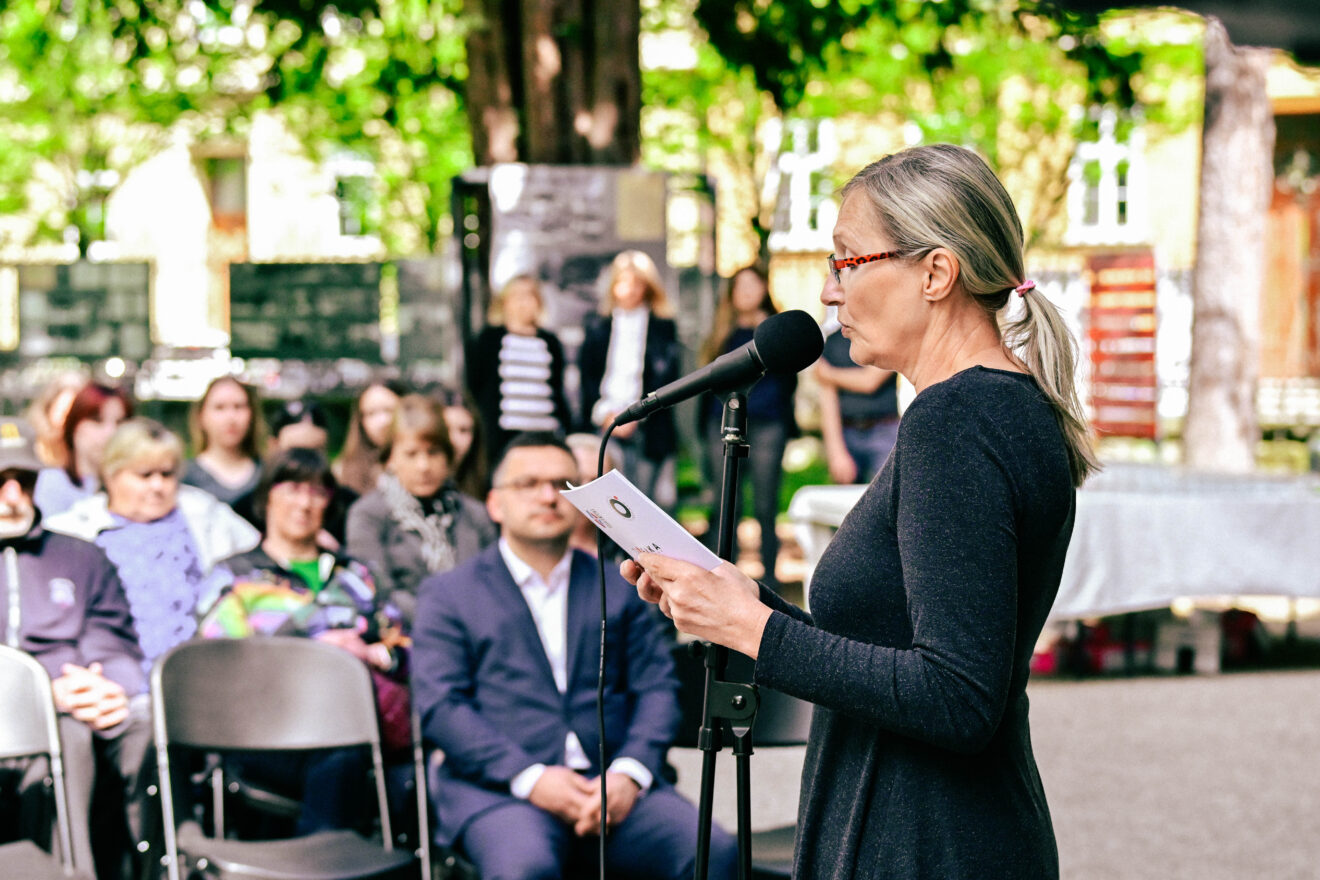 Ženska govori v mikrofon množici.